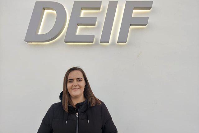 Christina Jørgensen, e-handel s specialist fra Erhvervsakademi Dania i Skive, står foran DEIFs logo, da hun har fået job der efter studiet