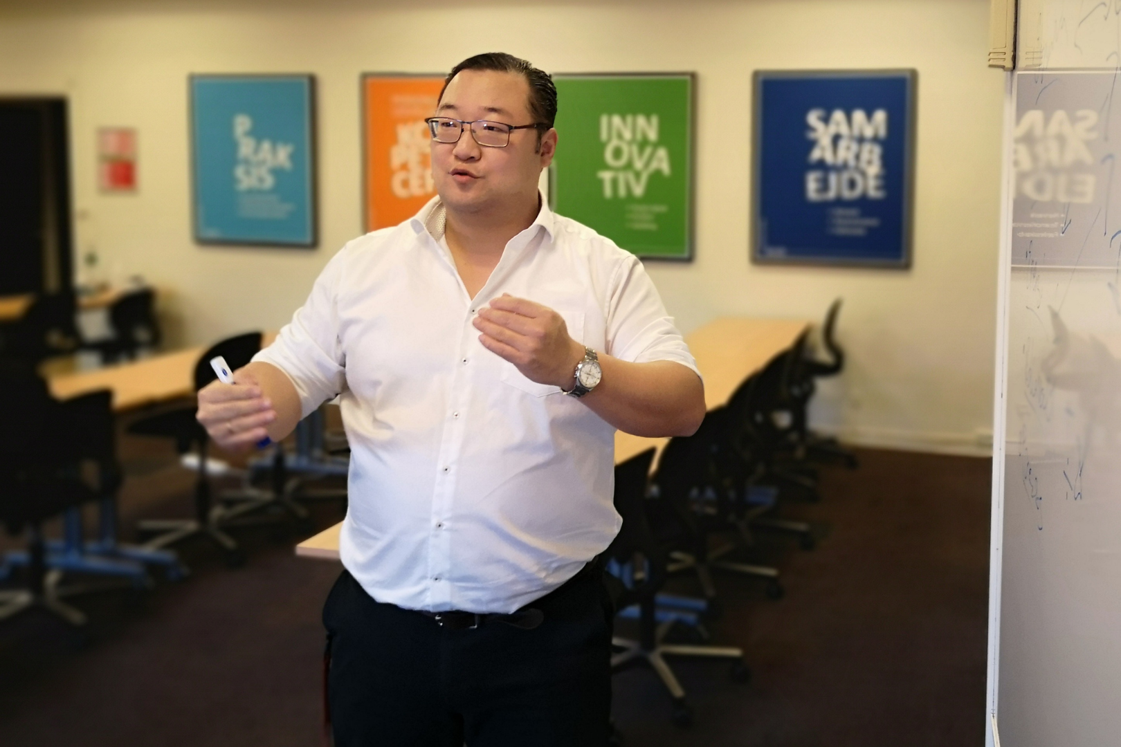 Lars Vejs-Petersen forklarer med armbevægelser om at være en god underviser i et klasselokale på Erhvervsakademi Dania i Silkeborg