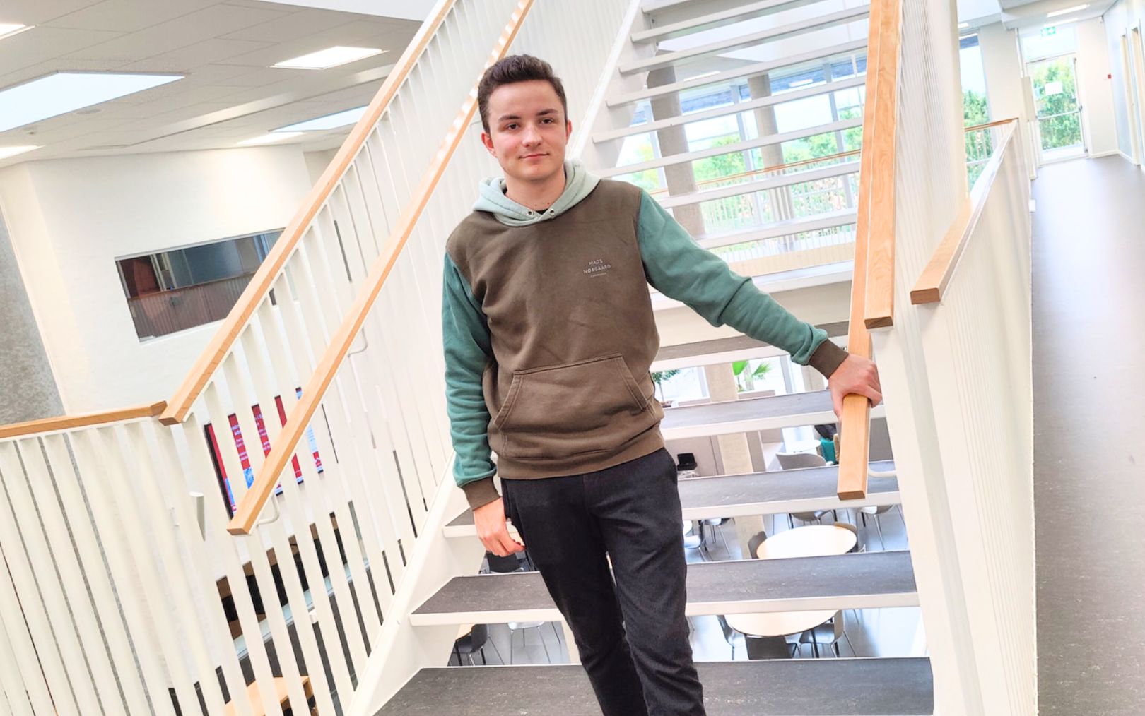 Frederik, der læser til el-installatør på Erhvervsakademi Dania i Randers, står op ad en trappe på campus