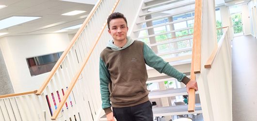 Frederik, der læser til el-installatør på Erhvervsakademi Dania i Randers, står op ad en trappe på campus