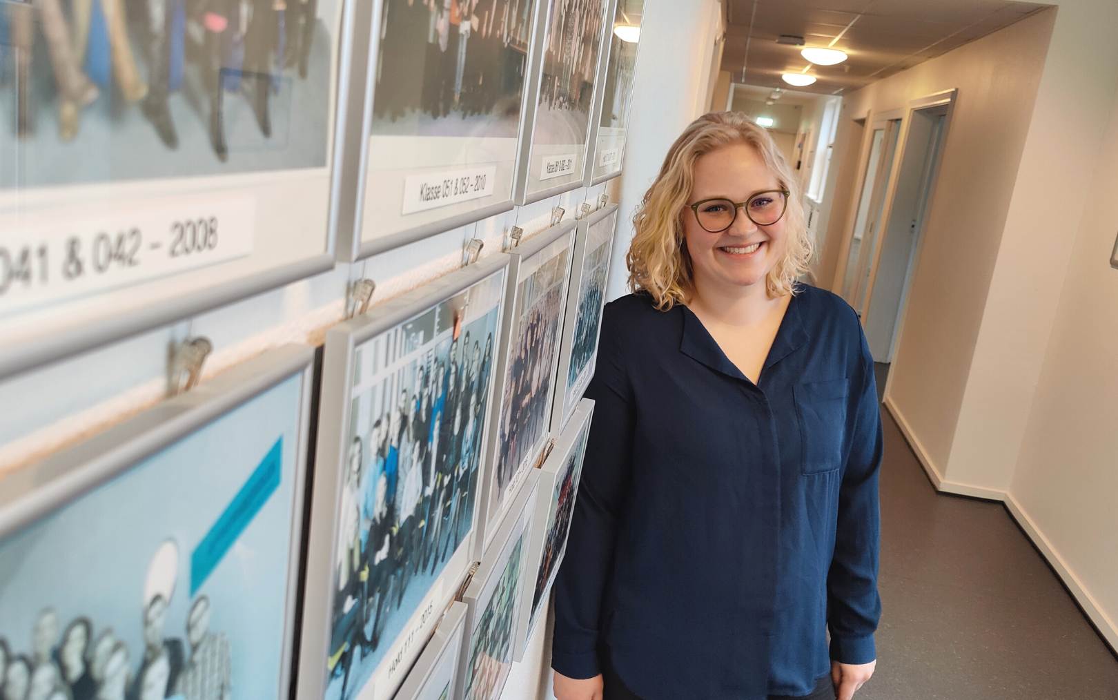 Michala, der har læst optiker på Dania, står op ad de sidste mange års dimissionsfotos fra uddannelsen