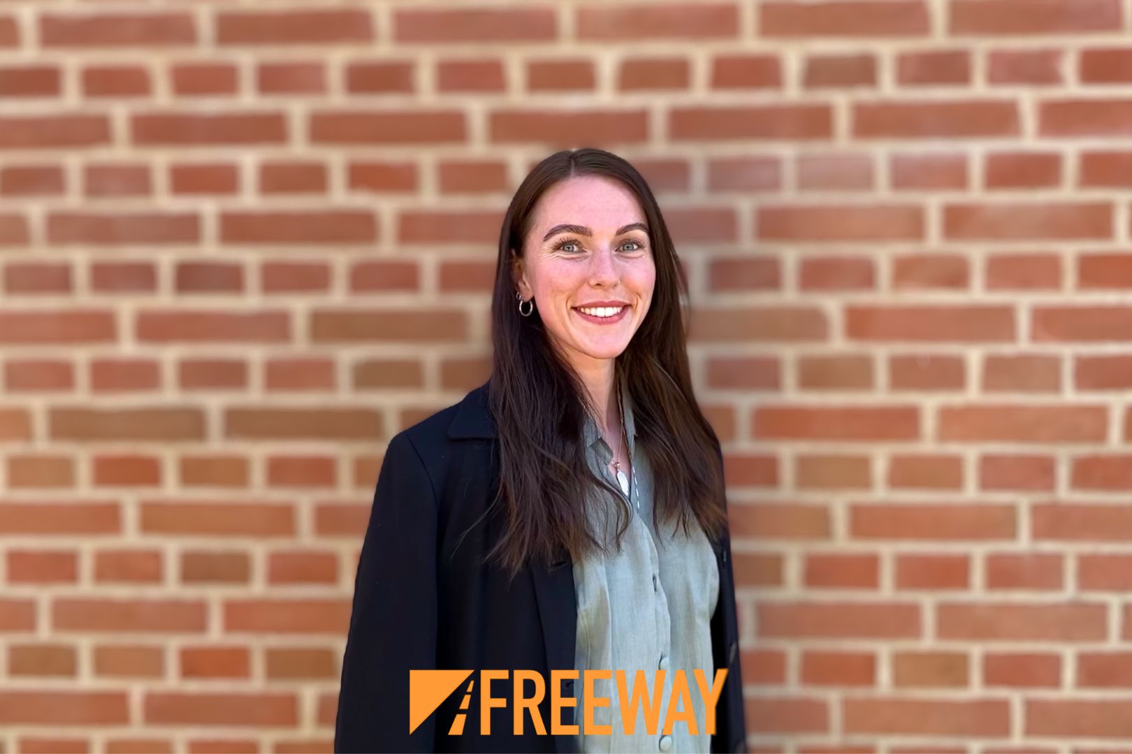 Anne-Sofie Groth, der er uddannet markedsføringsøkonom fra Erhvervsakademi Dania i Viborg, står foran en murstensvæg mens Freeways logo er i bunden, da hun arbejder der i dag