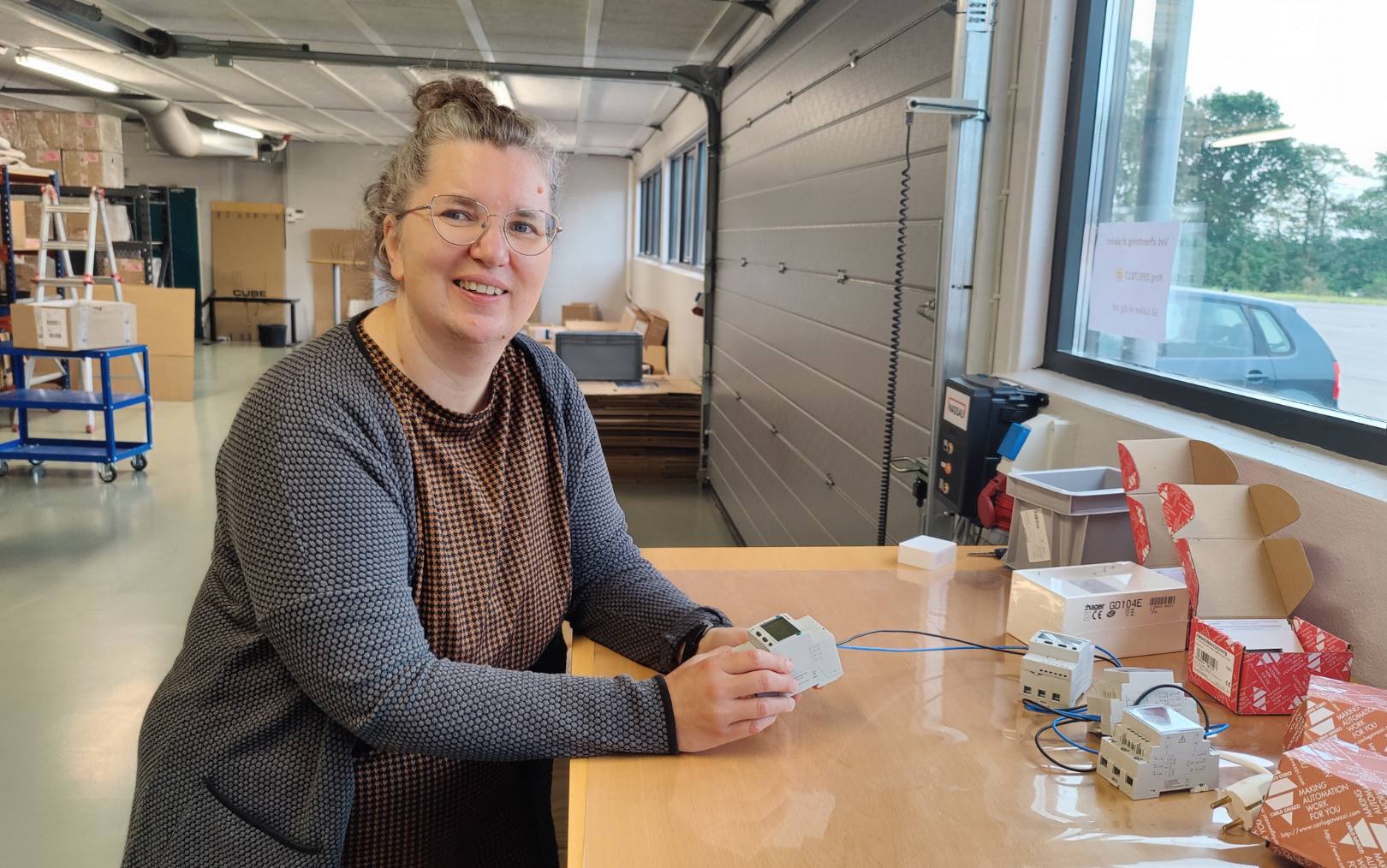 Britta, der er uddannet energiteknolog fra Erhvervsakademi Dania, står ved et højt bord med en måler i hånde, som de sælger ved DS Energy