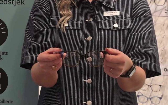 Ansøger Julie til optometri studiet online holder et par sorte briller