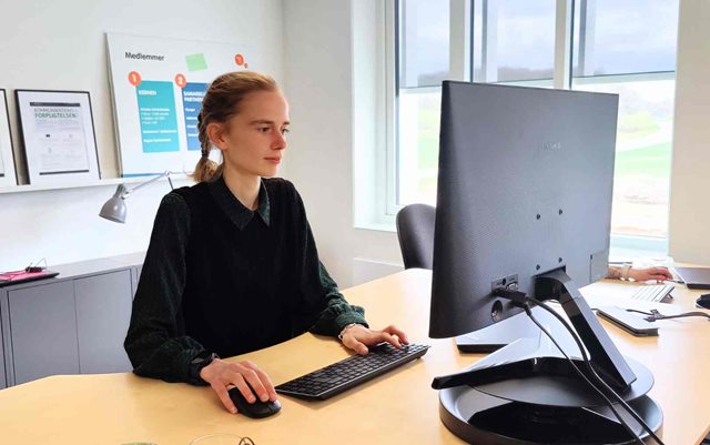Markedsførings-økonom Louise står ved sin computer og kigger ind i skærmen på work-live-stays kontor i Vejle, hvor hun har været i praktik