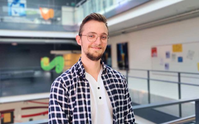 It-teknolog Nichlas Sprange står på campus i viborg og smiler, da han skal til finalen i Årets Erhvervsakademipraktik 2024 i København med sin praktikplads itm8