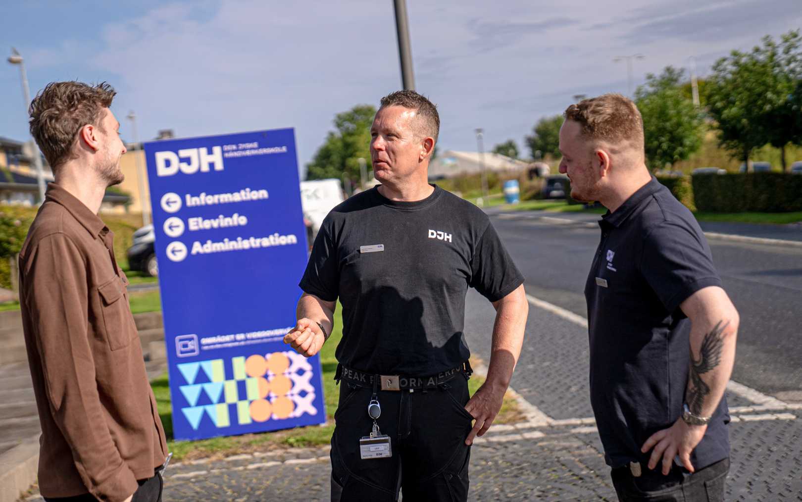 Tre undervisere fra Den Jyske Håndværkerskole står og snakker foran skiltet ind til bygningen