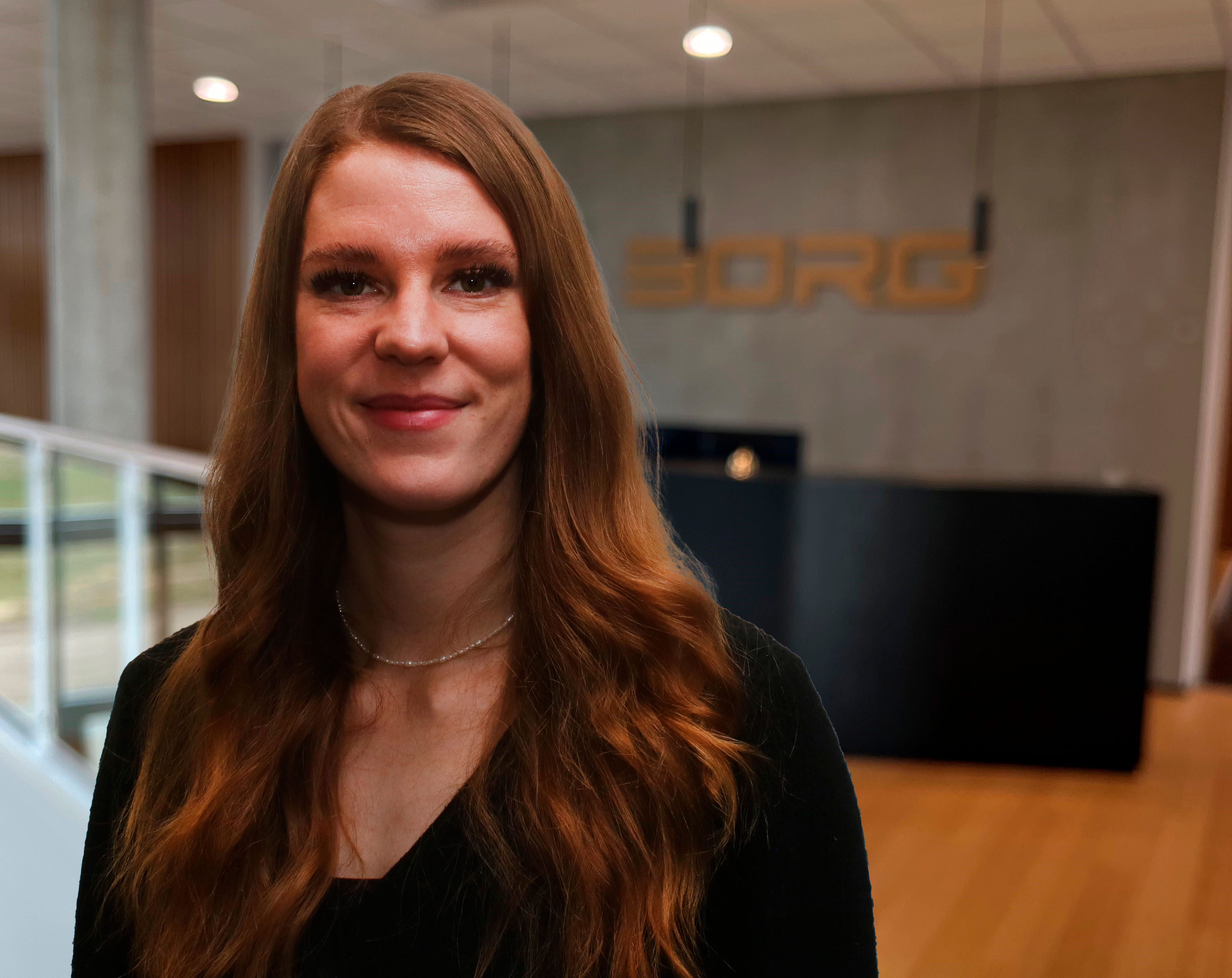 Julie, der har læst på erhvervsakademi Dania, står foran Borg logo og kigger på dig