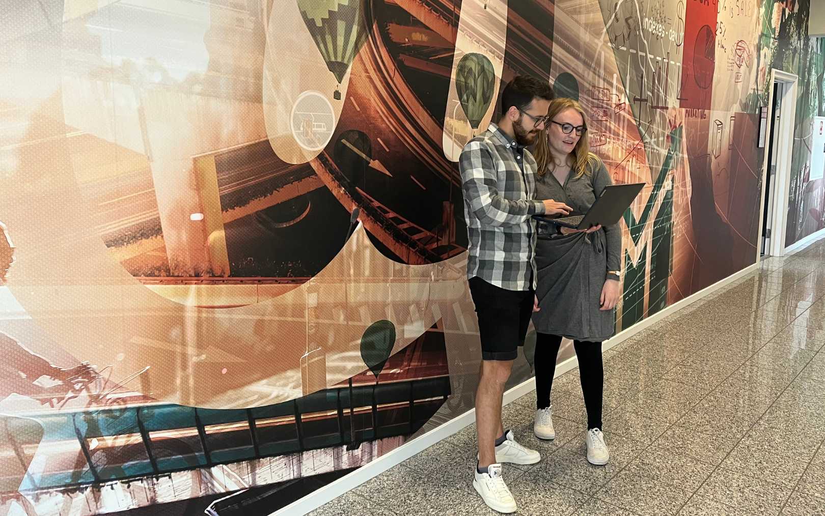 To studerende fra Erhvervsakademi Dania står på gangen og snakker 