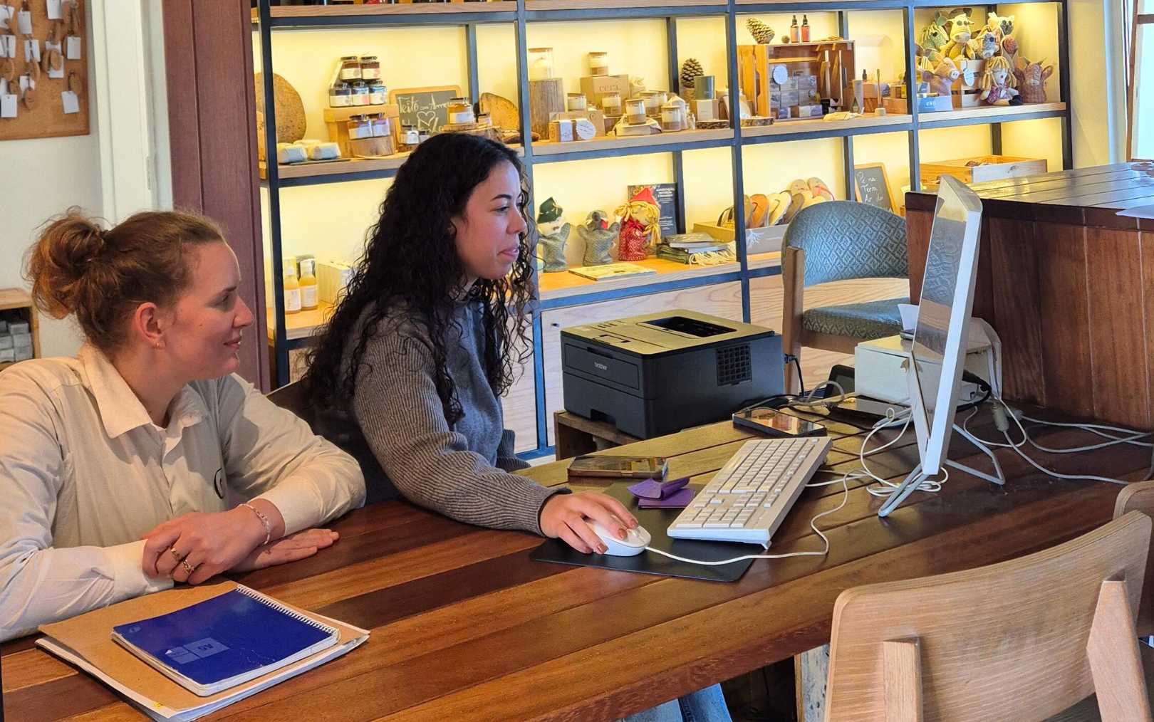 Lykke, der har læst på Erhvervsakademi Dania, sidder på hug bag en kollega ved hendes computer