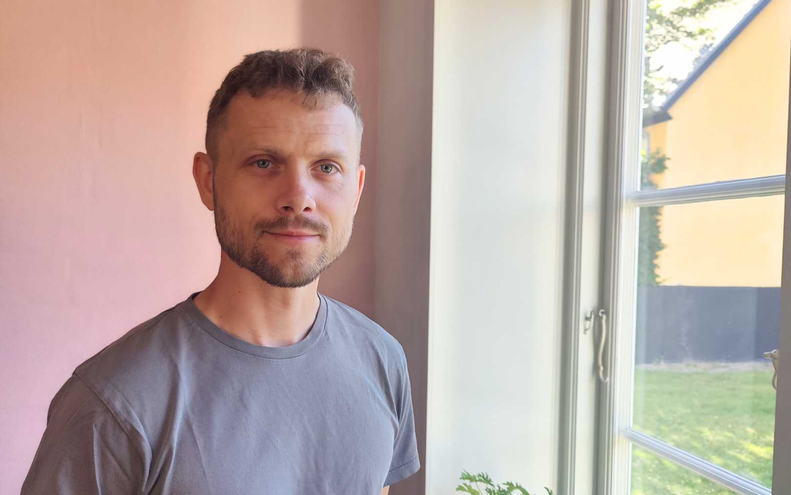 Casper Christensen, der har søgt ind på Erhvervsakademi Dania i Silkeborg, kigger på dig med en lyserød væg i baggrunden ved et vindue