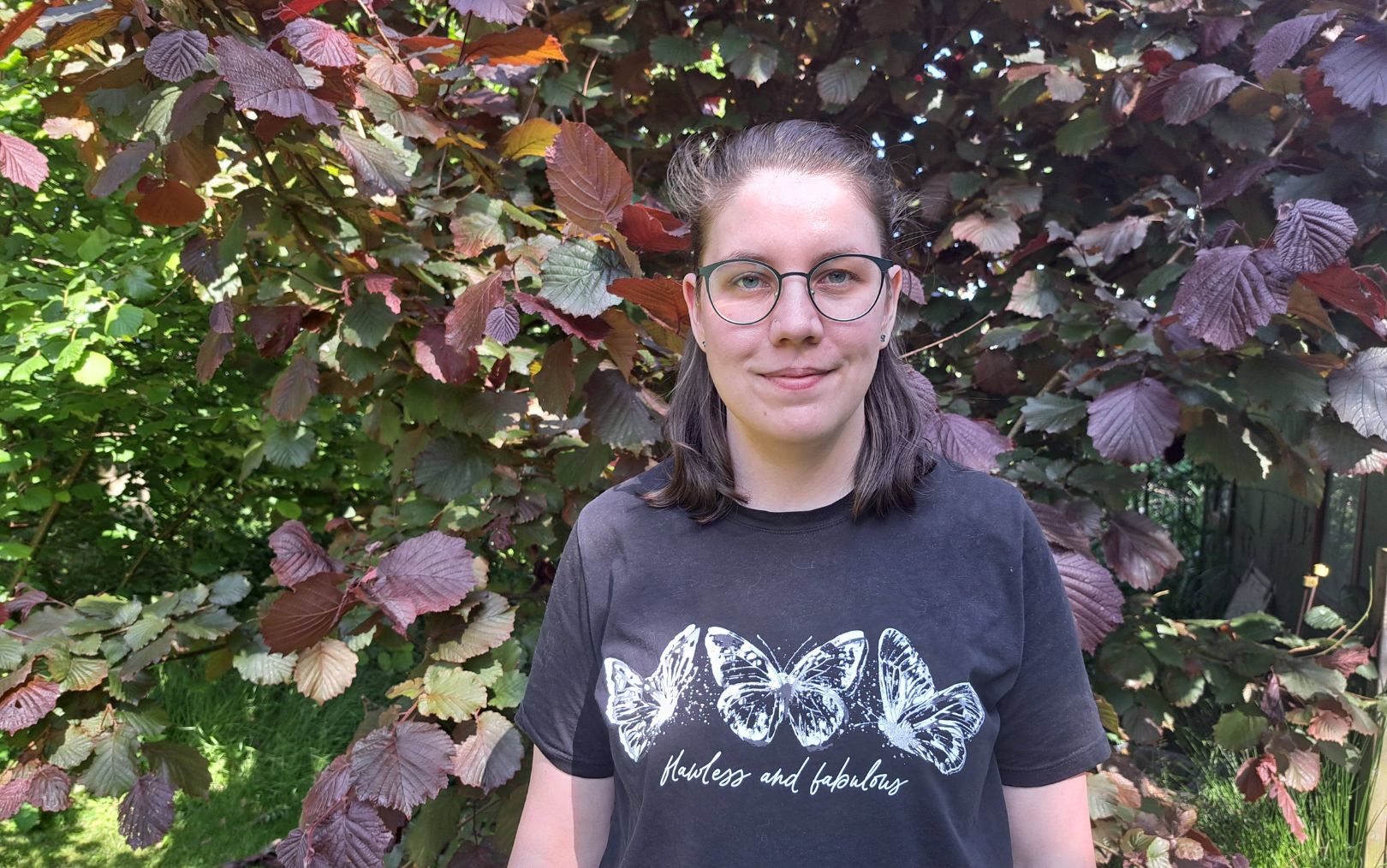 Henriette Paaske Bertelsen, der har søgt ind på Erhvervsakademi Danias datamatiker-studie, står i sin have foran en busk