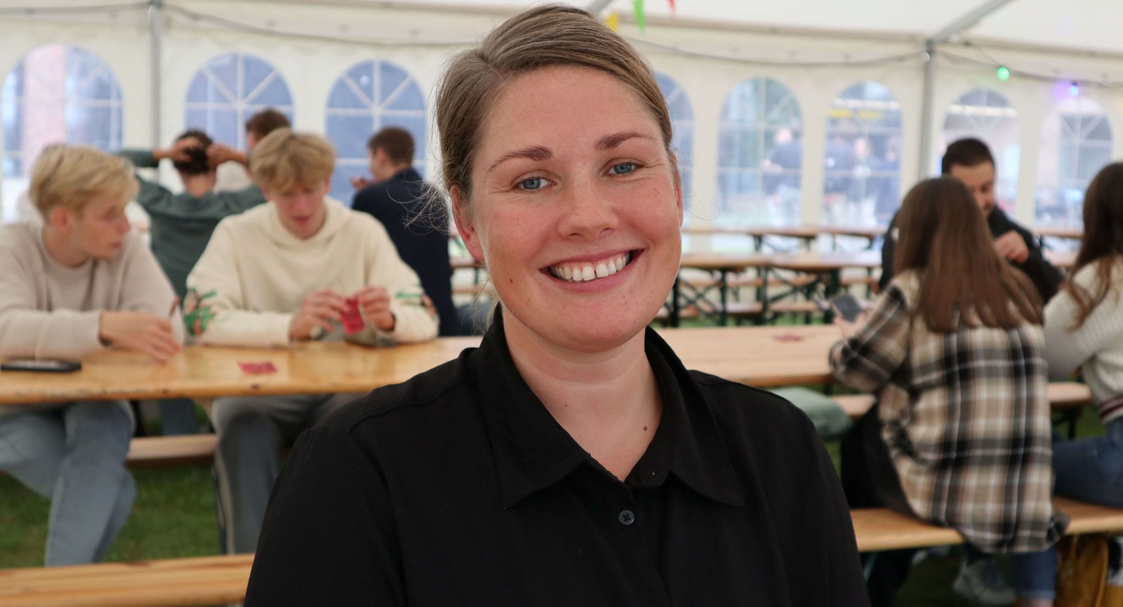 Loa Rasmussen - nystartet administrationsøkonom sidder sammen med andre i et stort telt