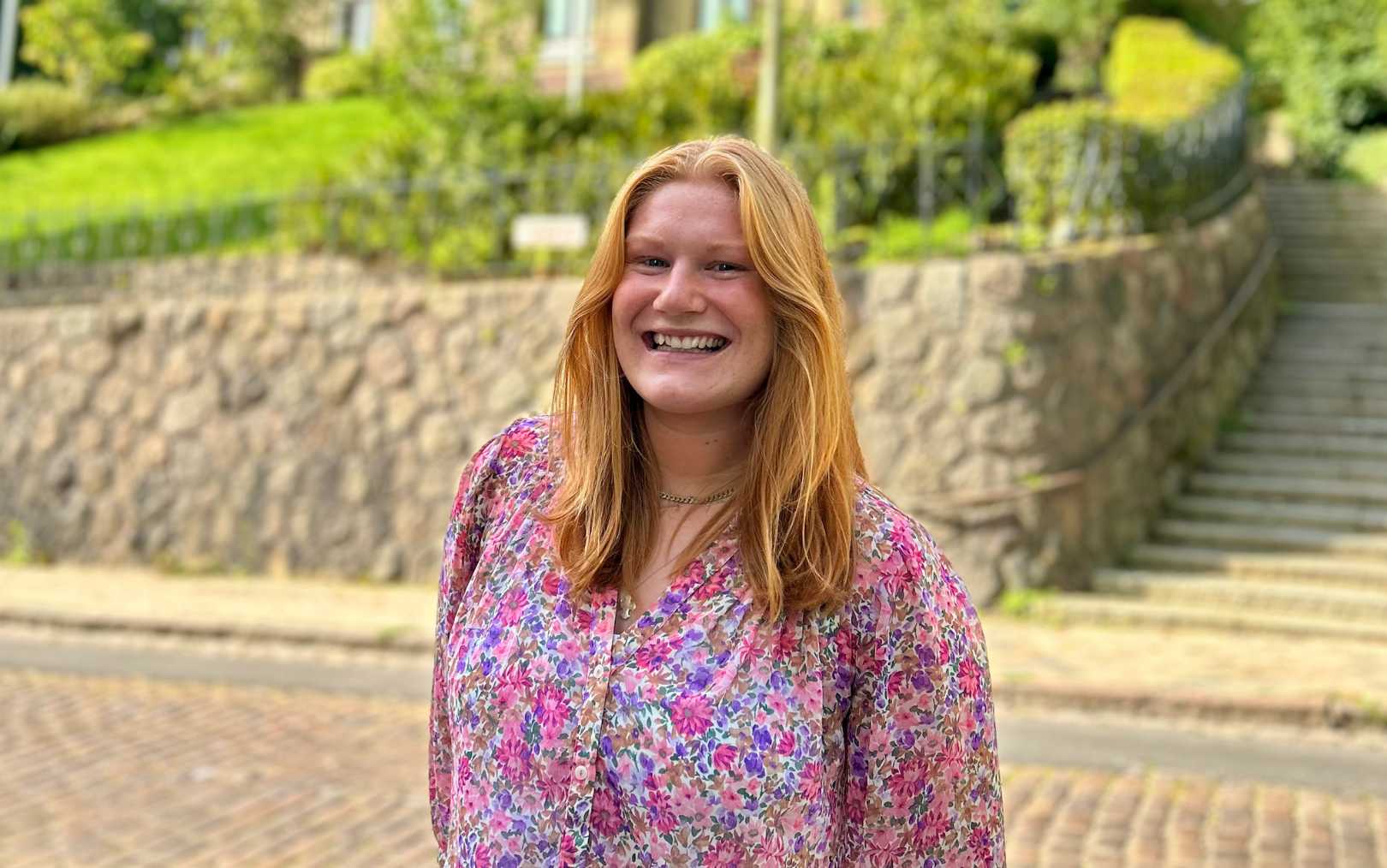 Marie Bogh Sørensen, der læser til handelsøkonom på Erhvervsakademi Dania, ses i blomstret bluse foran generalkonsulatet