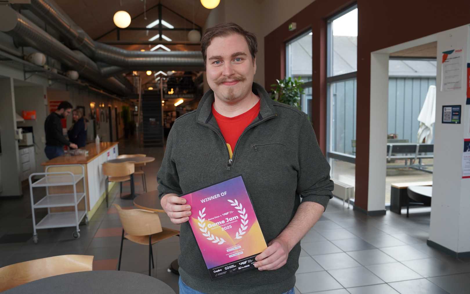 Jakob, der læser multimediedesign på Erhvervsakademi Dania Games i Grenå, står midt på campus med sin pris som vinder af Årets Game Jam i Viborg