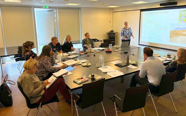 Flere ledere fra Fjordland er på efteruddannelse i ledelse på Erhvervsakademi Dania, hvor de sidder om et stort bord med en underviser ved tavlen