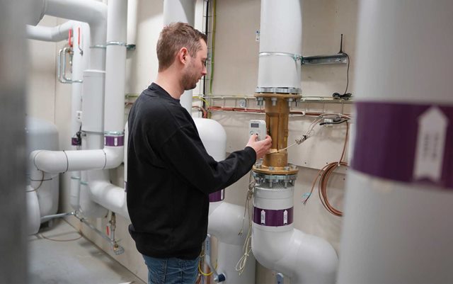 Dannie, der læser til energiteknolog på Erhvervsakademi Dania i Randers, står ved varmerør ved Ambercon