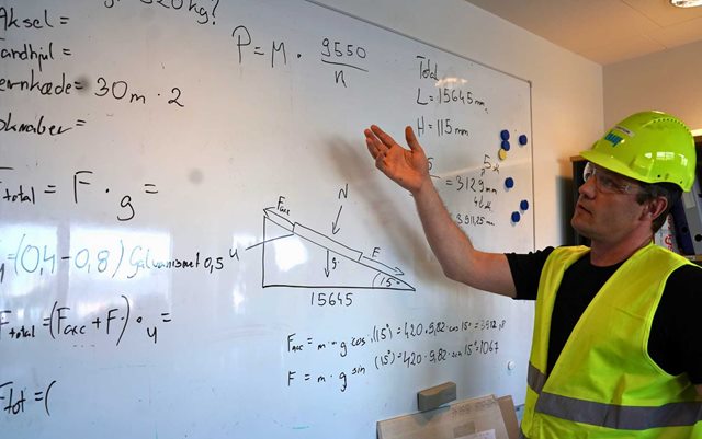 Krystian, der læser til produktionsteknolog på Erhvervsakademi Dania, fortæller om sine beregninger på en whiteboard tavle fuld af tal og grafer