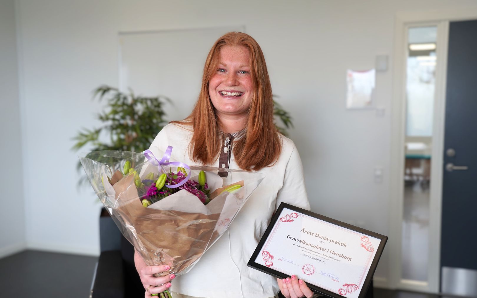 Handelsøkonom Marie Bogh Sørensen vinder årets Dania-praktik og står med sit diplom og en buket blomster